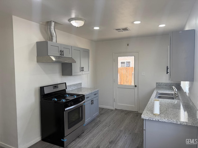 1708 Bower St, Bakersfield, CA 93305 - kitchen with stainless steel range with gas cooktop, under cabinet range hood, gray cabinets, dark wood-style flooring, and light stone counters