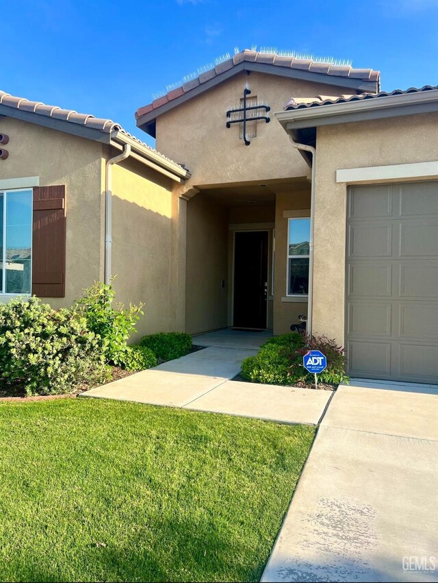 9909 Stockholm Pl, Bakersfield, CA 93306 - doorway to property featuring a garage and a lawn