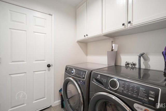 washroom with washing machine and clothes dryer, light tile patterned flooring, and cabinets