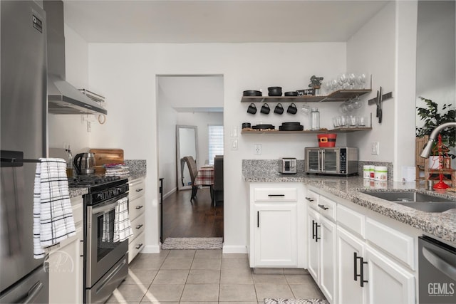 kitchen with white cabinets, wall chimney range hood, sink, light tile patterned flooring, and stainless steel appliances