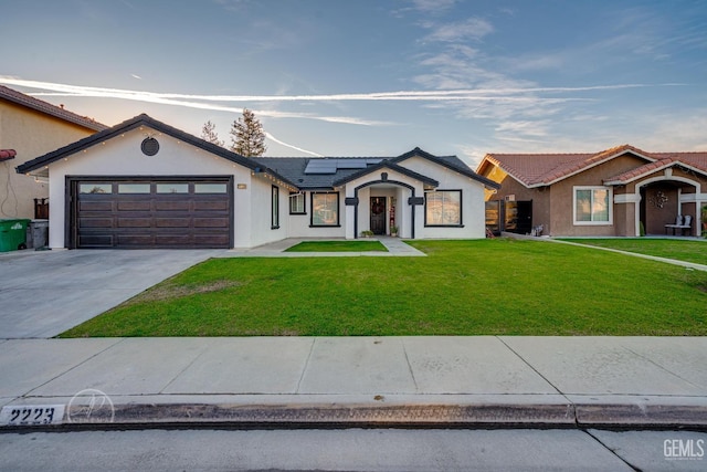 single story home featuring solar panels, a garage, and a yard