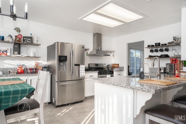 kitchen with a breakfast bar area, white cabinets, wall chimney exhaust hood, and stainless steel appliances