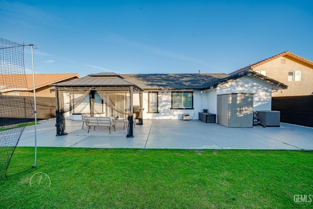 rear view of house featuring a gazebo, cooling unit, a patio, and a lawn