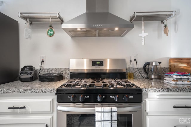 kitchen with light stone countertops, stainless steel range with gas stovetop, white cabinetry, and exhaust hood