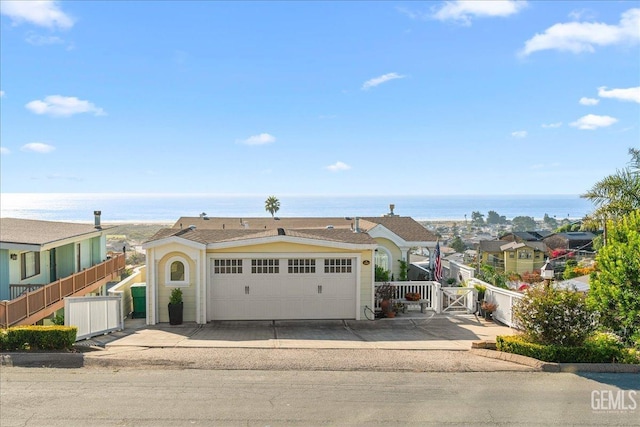 view of front of house with a gate, a water view, fence, and an attached garage