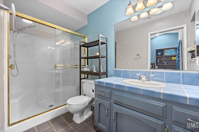 bathroom featuring toilet, a shower with door, tile patterned flooring, and vanity