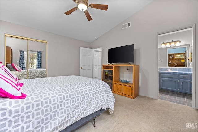 bedroom with vaulted ceiling, ensuite bath, a closet, ceiling fan, and light colored carpet