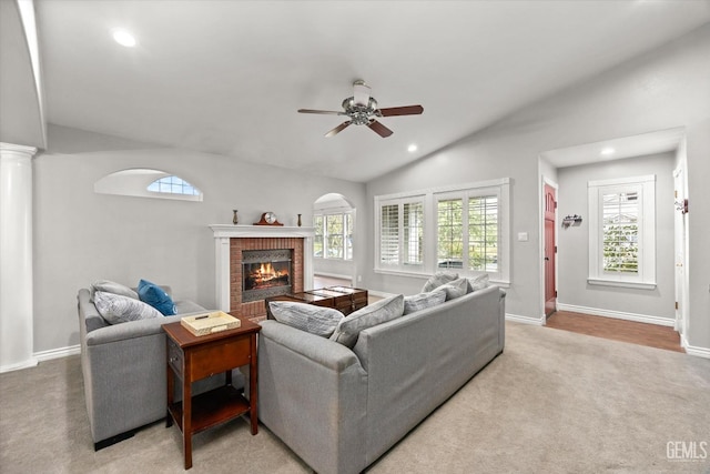 living room with a fireplace, ceiling fan, a healthy amount of sunlight, and lofted ceiling