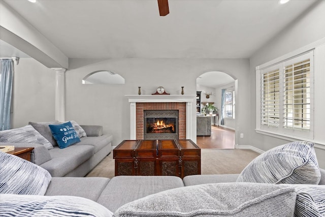 living room with a fireplace, ornate columns, and light colored carpet