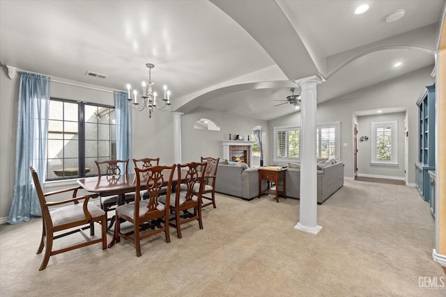 carpeted dining area with decorative columns, a wealth of natural light, vaulted ceiling, and a fireplace