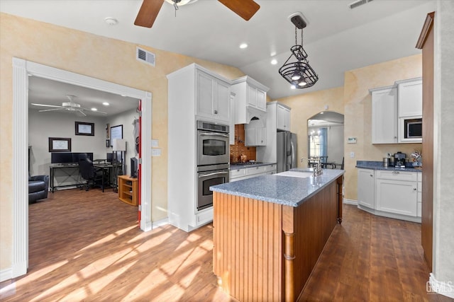 kitchen with a center island with sink, white cabinetry, stainless steel appliances, and light stone countertops