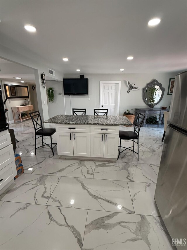 2404 Belvedere Ave, Bakersfield, CA 93304 - kitchen with freestanding refrigerator, recessed lighting, a center island, a breakfast bar area, and white cabinets