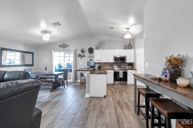 13160 Game Set Way, Bakersfield, CA 93306 - kitchen featuring appliances with stainless steel finishes, dark countertops, white cabinets, vaulted ceiling, and a peninsula