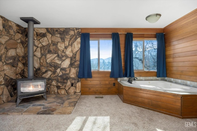 bathroom with a tub to relax in, a mountain view, a wood stove, and wood walls