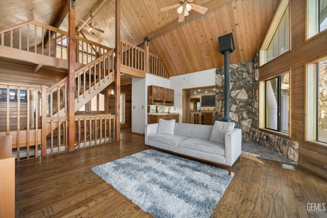 living room with wood ceiling, dark wood-type flooring, beamed ceiling, and a wood stove