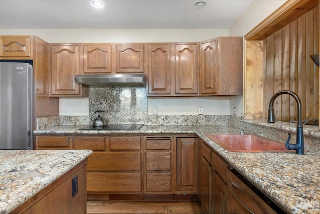 kitchen with sink, light stone counters, tasteful backsplash, stainless steel appliances, and light hardwood / wood-style floors