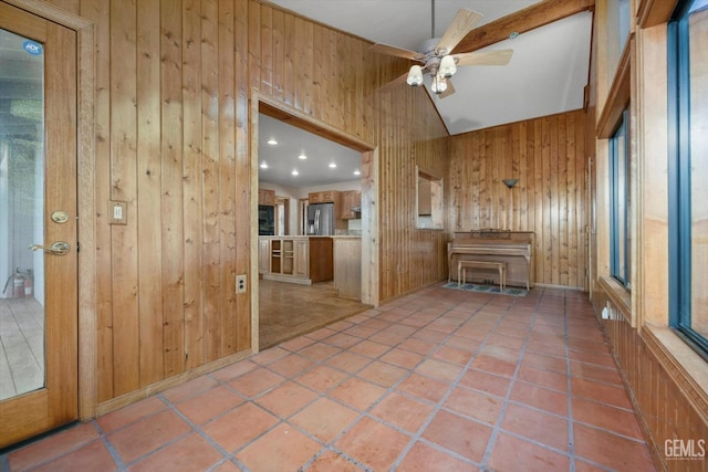 unfurnished living room with ceiling fan, light tile patterned floors, and wooden walls