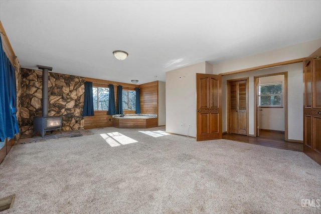 unfurnished living room with light carpet and a wood stove