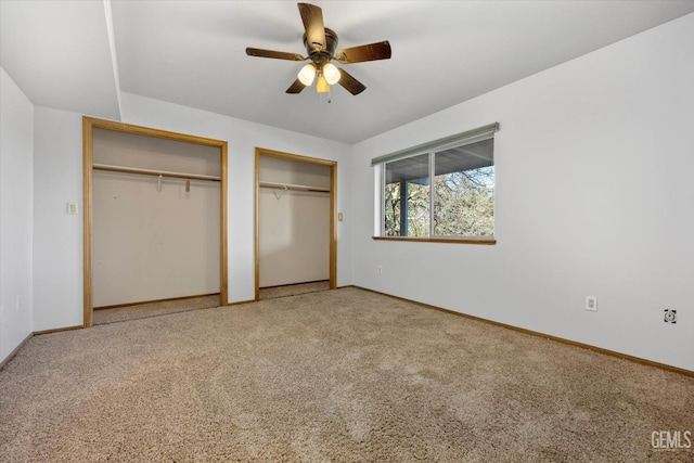 unfurnished bedroom with multiple closets, carpet floors, and ceiling fan