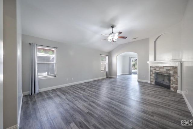 14211 Cedar Creek Ave, Bakersfield, CA 93314 - unfurnished living room featuring arched walkways, a ceiling fan, dark wood-style flooring, a stone fireplace, and vaulted ceiling