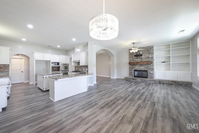 14211 Cedar Creek Ave, Bakersfield, CA 93314 - kitchen featuring a ceiling fan, appliances with stainless steel finishes, arched walkways, dark wood-type flooring, and a stone fireplace
