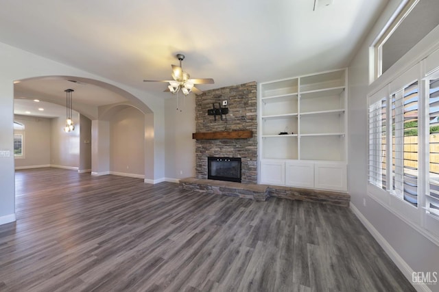 14211 Cedar Creek Ave, Bakersfield, CA 93314 - unfurnished living room featuring a ceiling fan, a stone fireplace, dark wood finished floors, arched walkways, and built in features