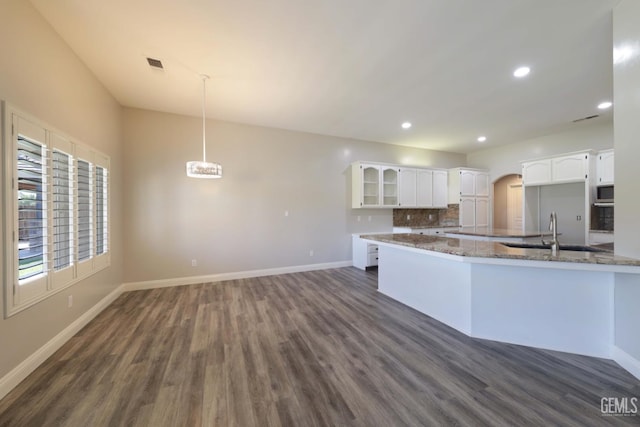 14211 Cedar Creek Ave, Bakersfield, CA 93314 - kitchen featuring dark wood-style flooring, white cabinets, arched walkways, dark stone countertops, and recessed lighting