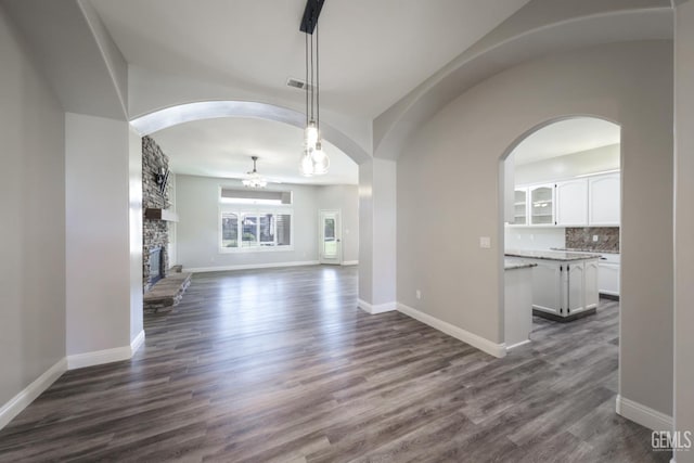 14211 Cedar Creek Ave, Bakersfield, CA 93314 - unfurnished living room featuring dark wood-type flooring, arched walkways, and a fireplace
