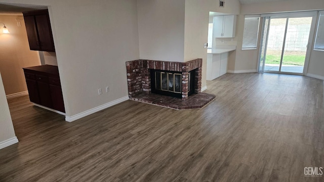 unfurnished living room with a fireplace, wood finished floors, and baseboards