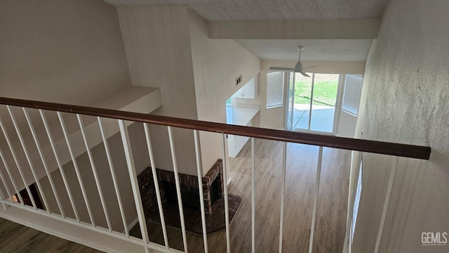 staircase featuring a textured ceiling, wood finished floors, and a ceiling fan