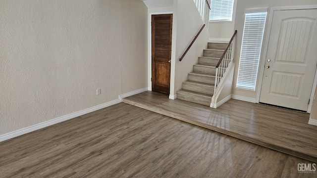 foyer with baseboards, stairway, wood finished floors, and a textured wall