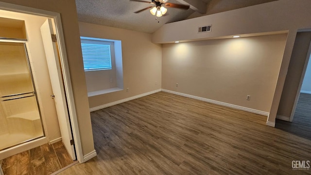 unfurnished bedroom with baseboards, visible vents, dark wood-style floors, vaulted ceiling with beams, and a textured ceiling