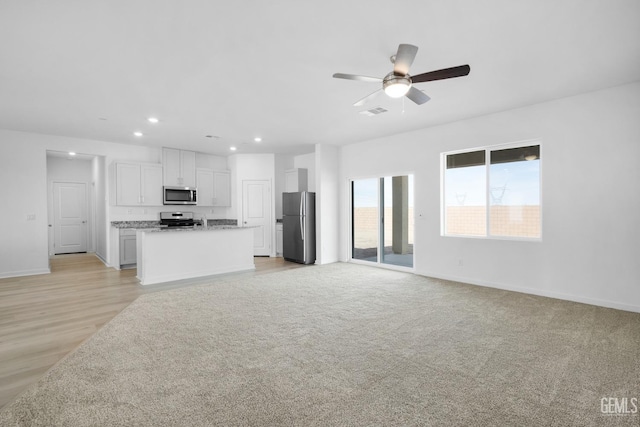 unfurnished living room featuring light carpet, visible vents, baseboards, ceiling fan, and recessed lighting