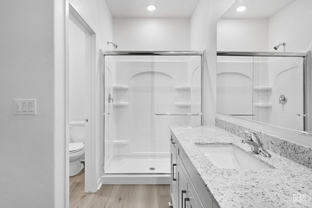 full bath featuring vanity, wood finished floors, toilet, and a shower stall