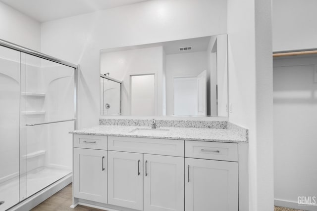 bathroom with a stall shower, visible vents, vanity, and wood finished floors