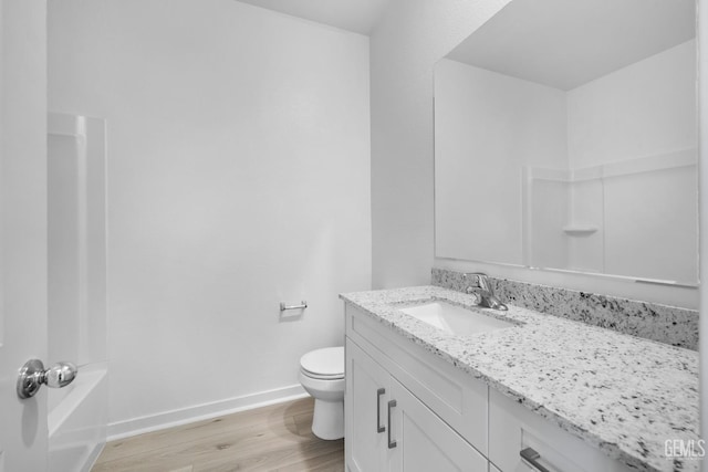 full bathroom with toilet, wood finished floors, vanity, and baseboards