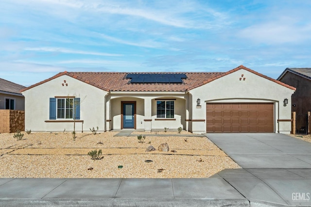 mediterranean / spanish-style home with concrete driveway, a tile roof, roof mounted solar panels, and stucco siding