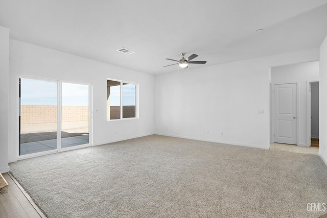 empty room with baseboards, light colored carpet, visible vents, and a ceiling fan