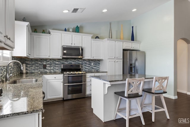 kitchen with visible vents, lofted ceiling, a sink, appliances with stainless steel finishes, and backsplash