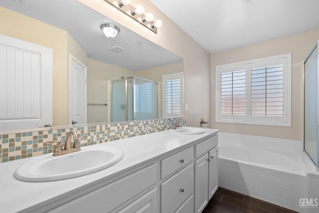 bathroom featuring a sink, decorative backsplash, a bath, and a shower stall