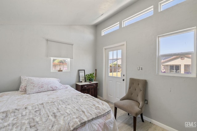 bedroom featuring baseboards, light wood-style flooring, and a towering ceiling