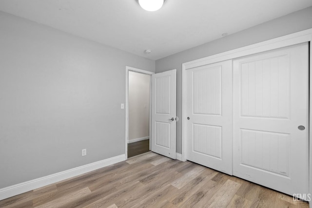 unfurnished bedroom with baseboards, light wood finished floors, and a closet