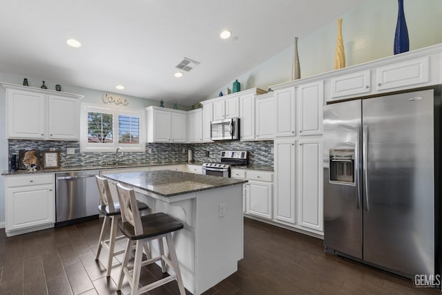 kitchen with appliances with stainless steel finishes, decorative backsplash, vaulted ceiling, and visible vents