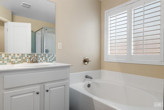 bathroom with decorative backsplash, a bath, visible vents, an enclosed shower, and vanity