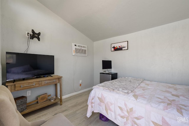 bedroom featuring baseboards, a wall mounted air conditioner, wood finished floors, and lofted ceiling
