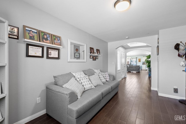 living area featuring arched walkways, baseboards, and dark wood-style floors