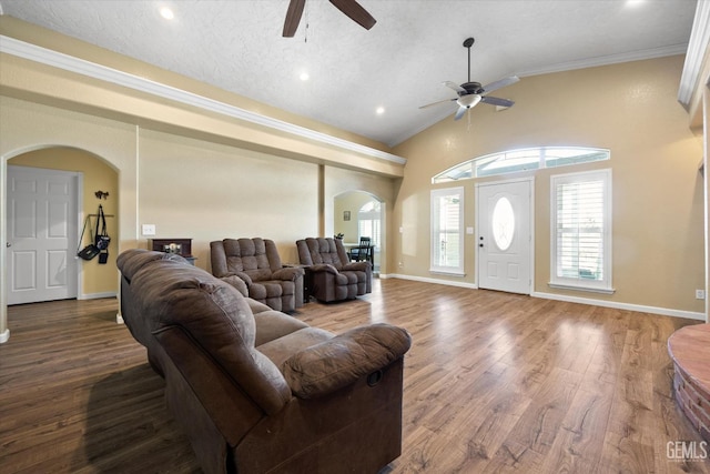 living area with arched walkways, a ceiling fan, crown molding, wood finished floors, and baseboards