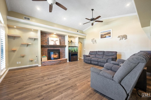 living area featuring ceiling fan, a brick fireplace, ornamental molding, vaulted ceiling, and wood finished floors