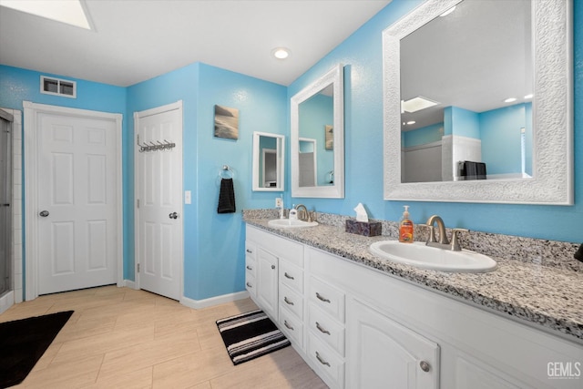 bathroom with double vanity, a shower with shower door, and baseboards