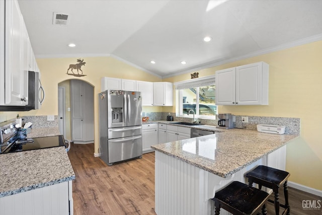 kitchen featuring stainless steel appliances, a peninsula, a sink, light wood-style floors, and ornamental molding